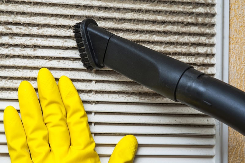 Hand in yellow glove and vacuum cleaner pipe