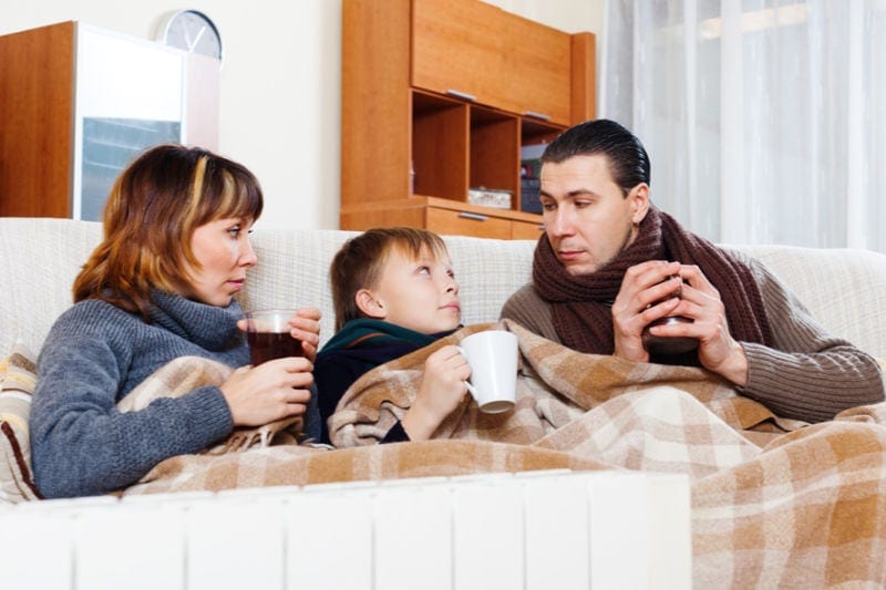 Cold family under blanket, worried about their heat pump being used for first time. Air-Ton Heating & Air Conditioning blog image.